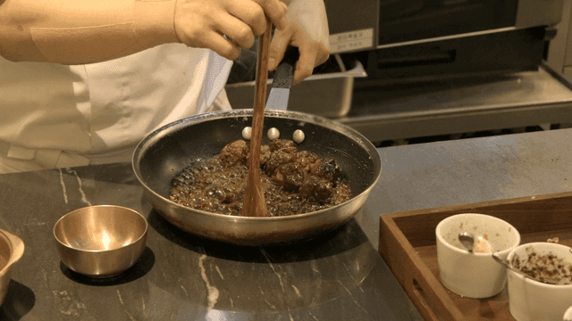 Chef cooking meatballs in a pan