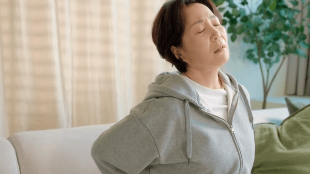 Elderly woman experiencing back pain