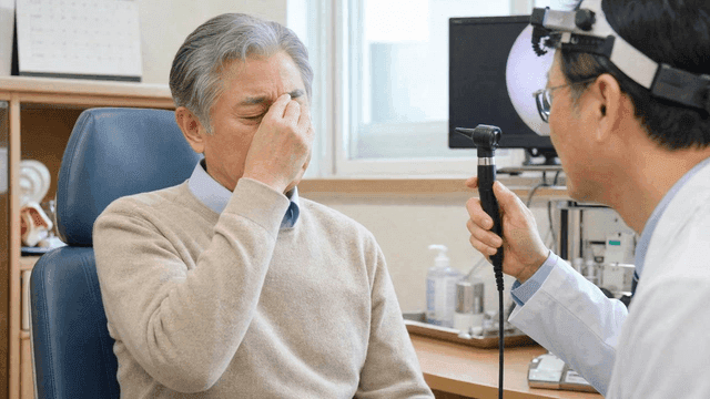 Doctor examining elderly person holding their nose in pain