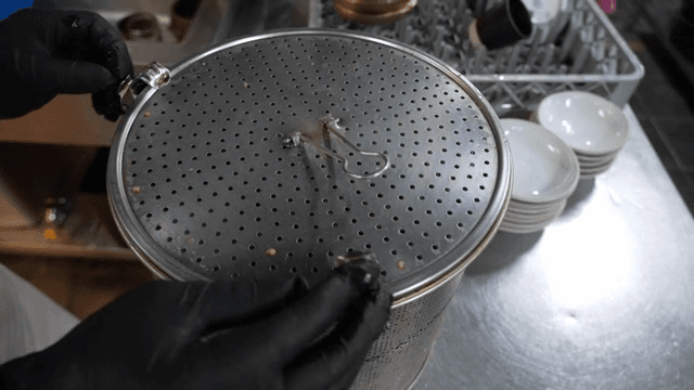 A person handling a pot lid