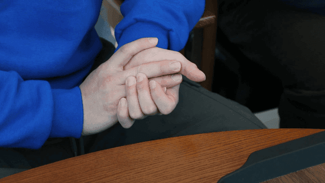 Hands folded on table