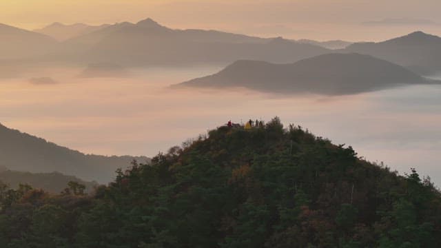 안개 낀 산 위 일출이 물들인 하늘