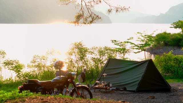 Early morning camping by the serene lakeside with tents and motorbikes