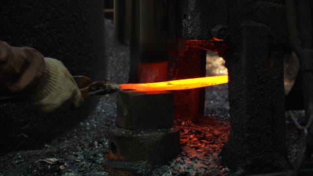 Worker forging metal in a factory