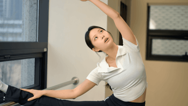 Young woman stretching by the window