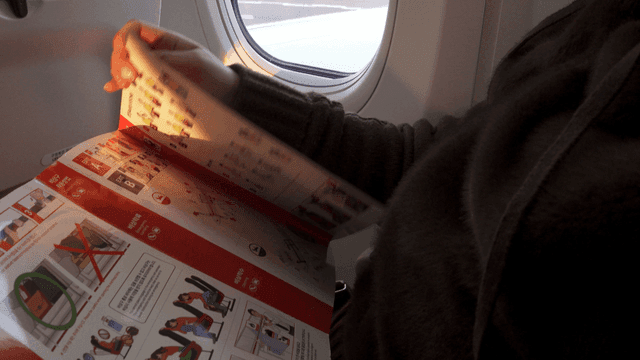 Passenger reading safety instructions on a plane