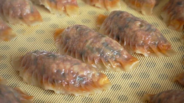 Kimchi dumplings steaming in a steamer in the kitchen