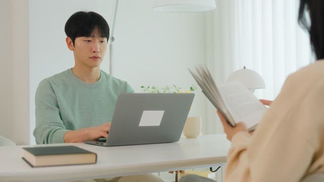 밝은 인테리어의 거실 테이블에서 노트북을 사용하는 남자