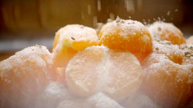 Sugar and nuts sprinkled on top of stacked tangerines