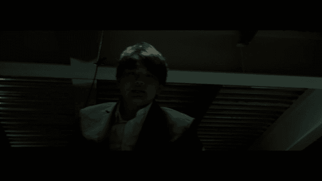 실내에서 아래를 내려다보는 정장 입은 남성