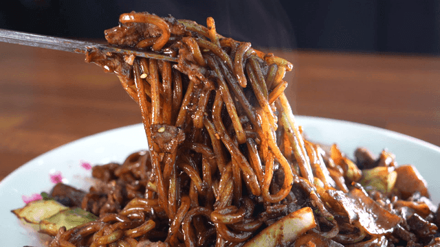 Chopsticks picking up steaming jajangmyeon