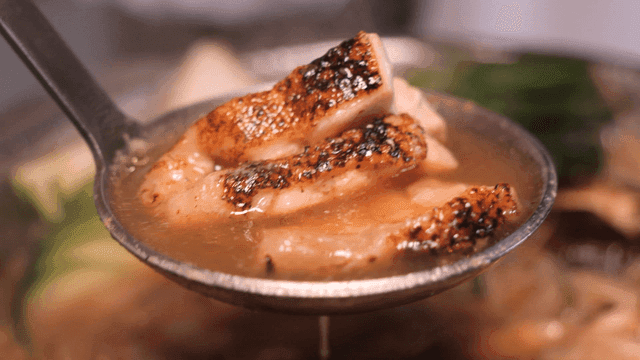Ladle filled with chicken stew with roasted chicken and vegetables
