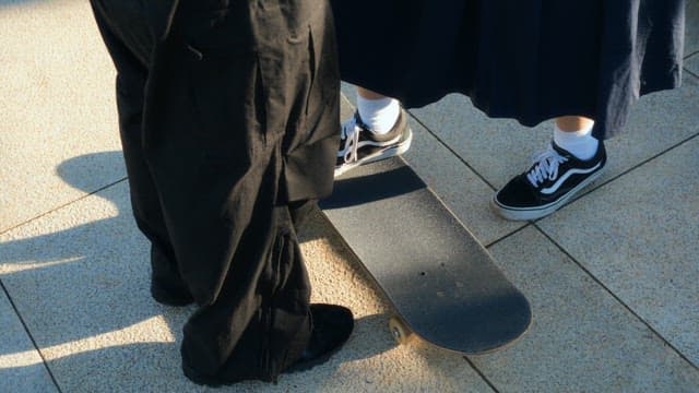 스케이트보드를 타는 여성을 도와주는 남성