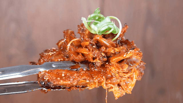 Spicy, crunchy braised pork ribs scooped out with tongs