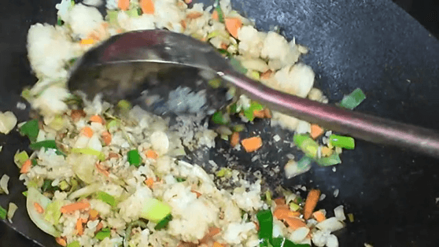 Stir-frying vegetables and rice in a wok