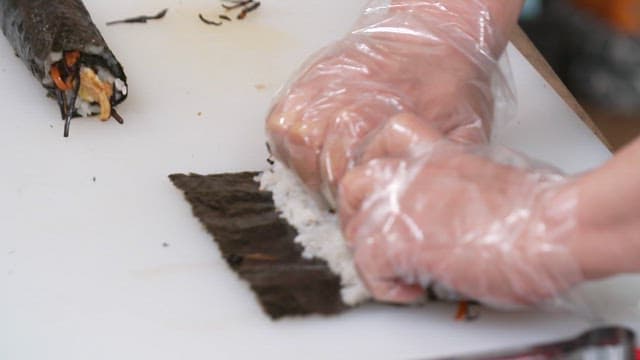 Hand rolling kimbap on a cutting board