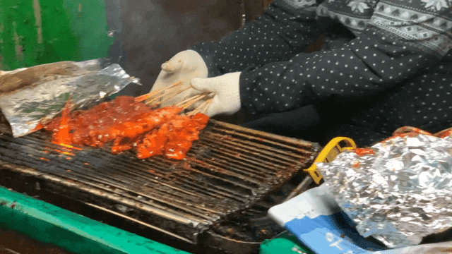 길거리에서 매운 닭꼬치를 굽는 상인