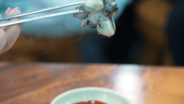 Chopstickful of oysters dipped in red soy sauce