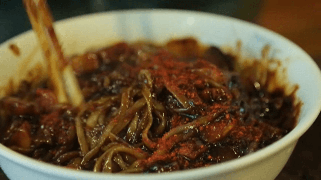 고춧가루를 넣어 짜장면을 비비는 모습