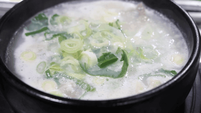 Beef soup with green onions boiling in earthenware pot