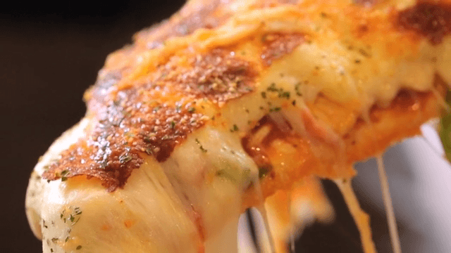 Cheesy pizza slice being lifted
