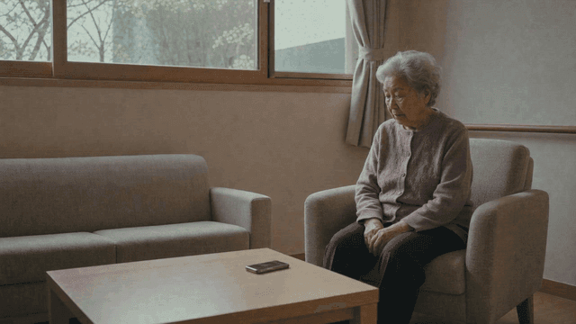 Elderly woman sitting in quiet room looking at her cell phone