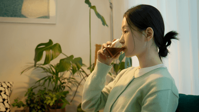 Side view of woman drinking coffee in cozy room