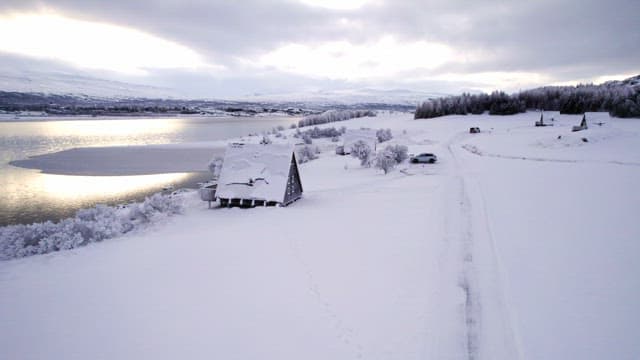 Snow-covered landscape with a cabin by a lake