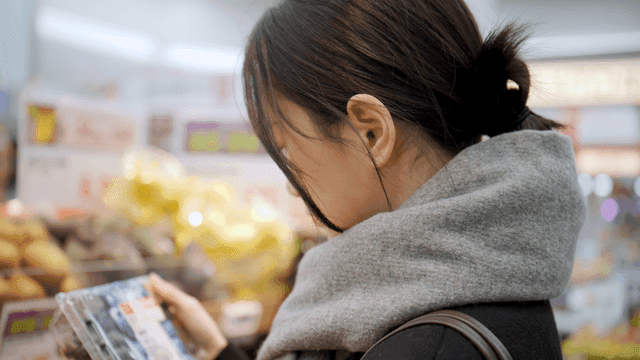 Young woman shopping for groceries and fruits at supermarket
