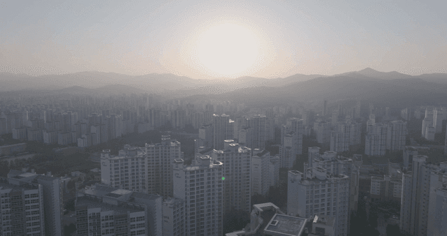 A cityscape with a setting sun over mountains