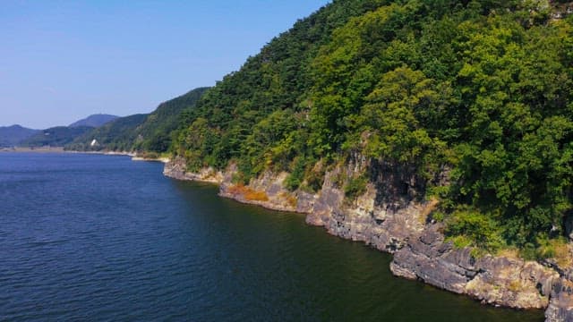 Scenic view of forested cliffs along a river on a sunny day