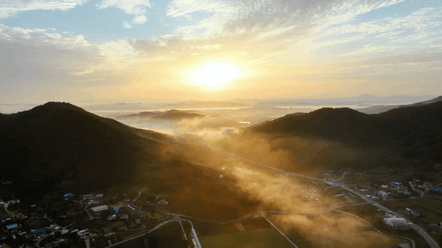 안개 낀 산과 마을 위로 떠오르는 해