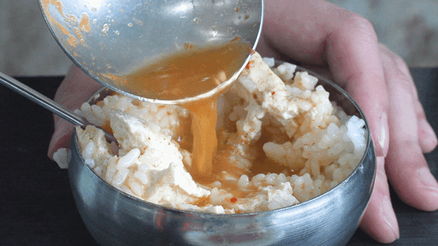 Pouring broth over rice and tofu