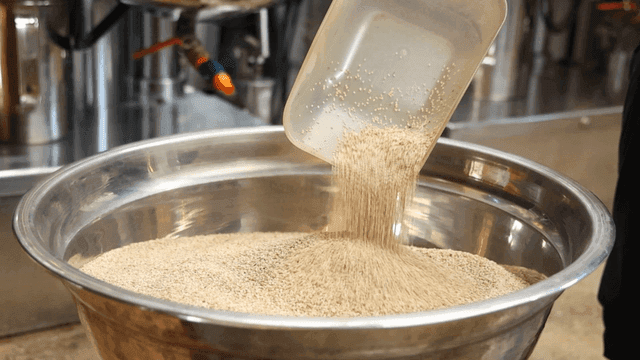 Sesame seeds poured into large metal bowl
