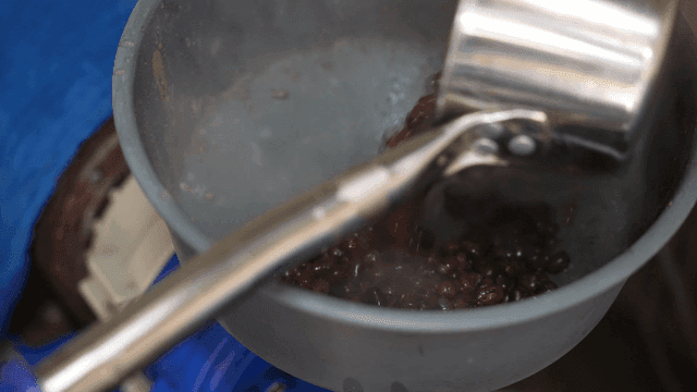 Boiled red beans being put from pot into blender
