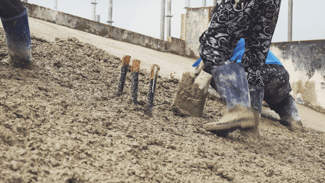 경사면에서 젖은 콘크리트를 다듬는 작업자들