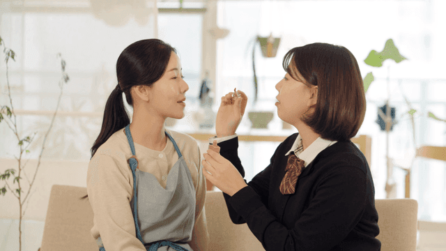 Daughter applying lip gloss to her mother's lips
