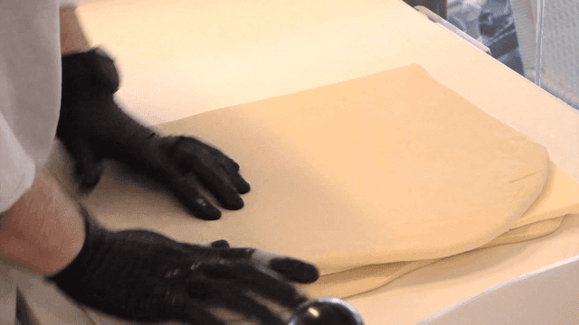 Baker placing butter between dough layers on counter