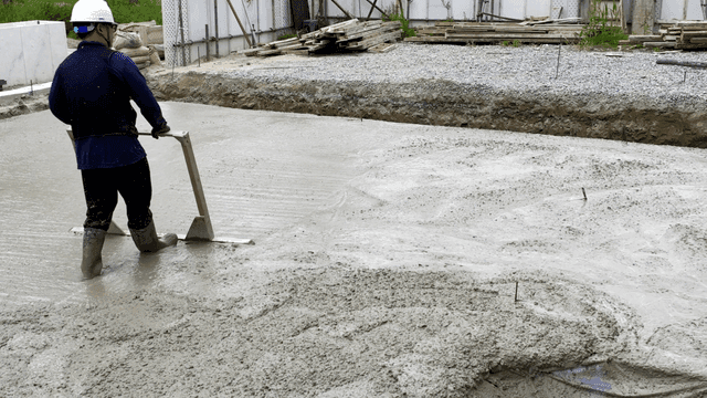 Worker leveling wet concrete at a site