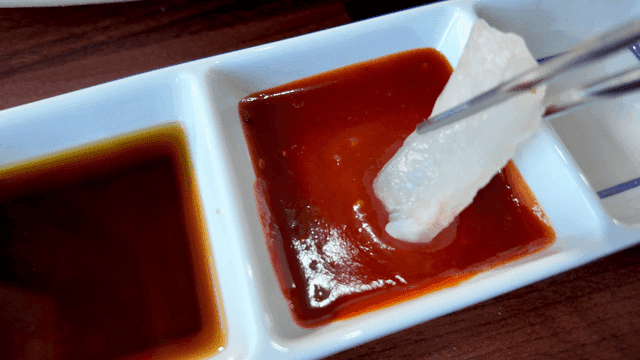 Fresh sea bass sashimi dipped in soy sauce