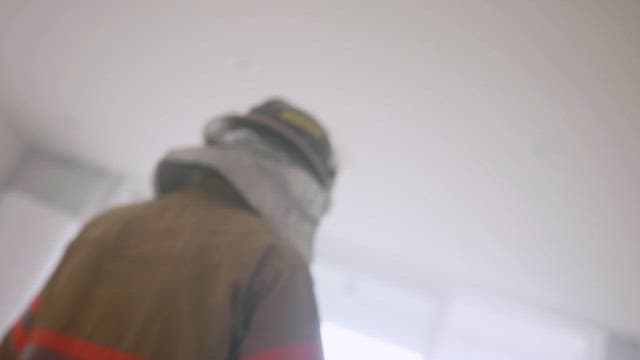 Firefighter and child standing side by side in a bright living room