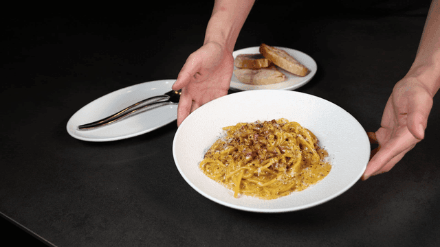 A plate of carbonara pasta being served