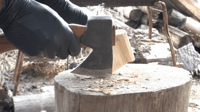 야외에서 도끼로 나무를 자르는 모습