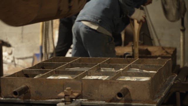 Sand being poured into a mold in a workshop