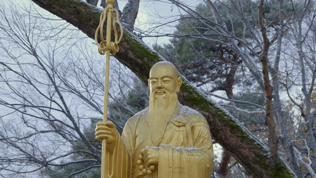 Golden statue of a monk in a snowy forest