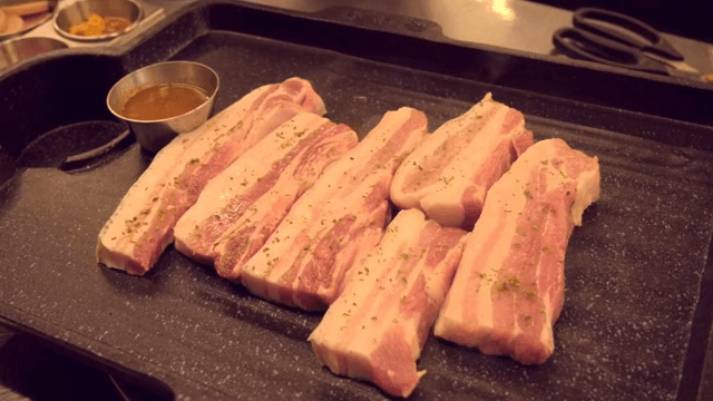 Raw pork belly slices on a grill