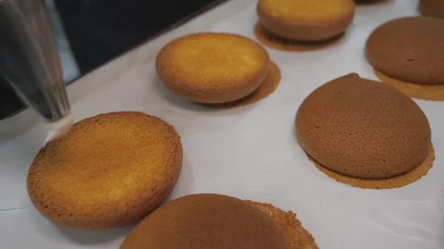 Piping cream onto freshly baked cookies in a bakery