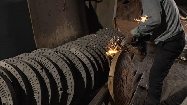 Worker grinding metal parts in a factory