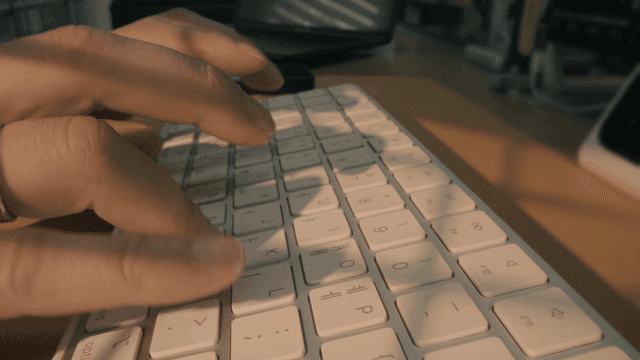 Hands typing on keyboard in dark room
