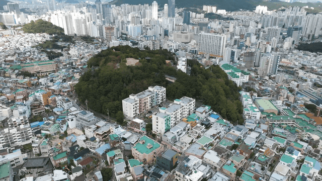 Aerial view of a city with green hills